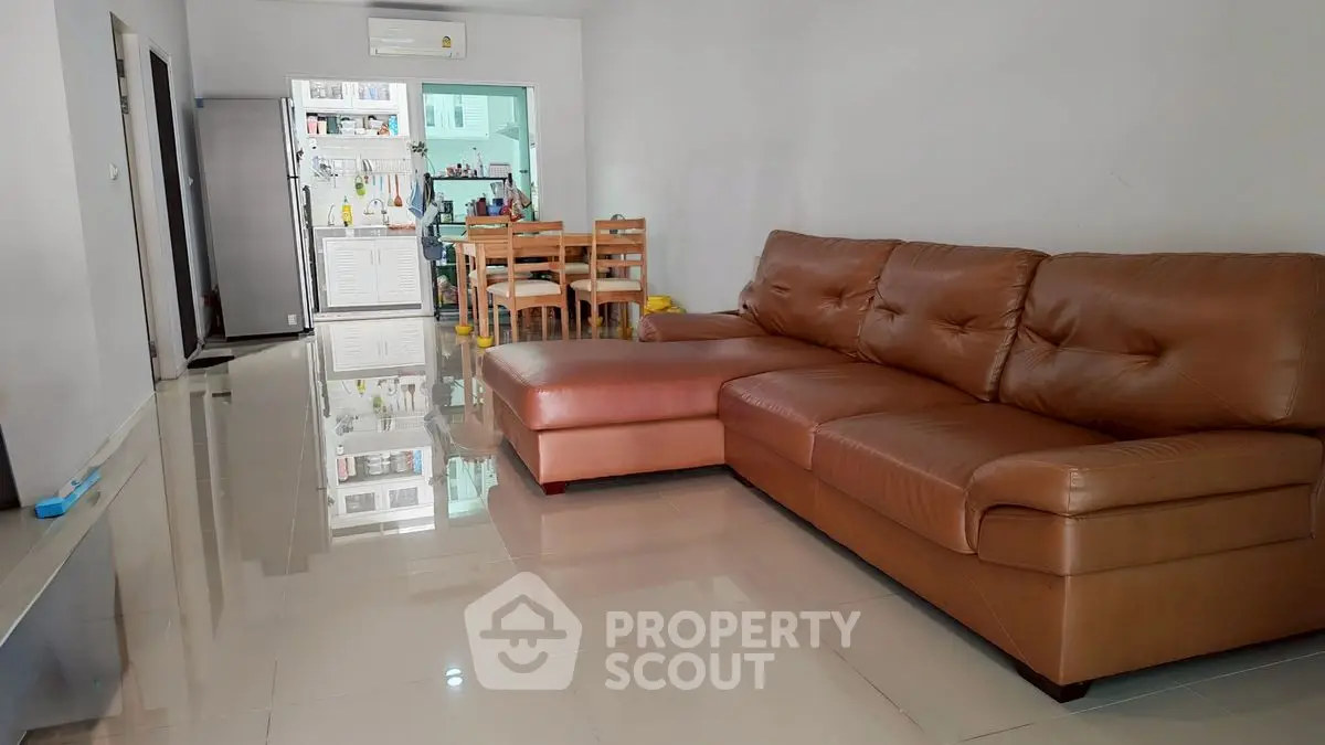 Spacious living room with modern leather sofa and open kitchen layout