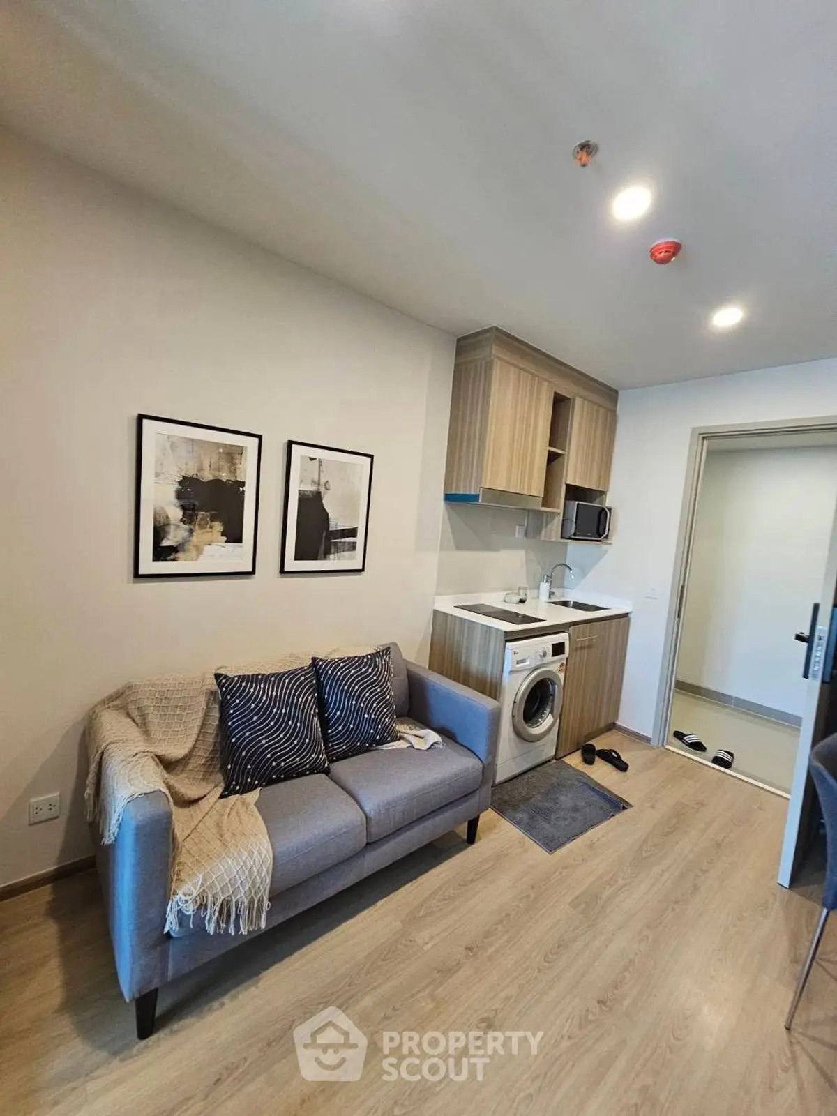 Modern compact living room with integrated kitchen and washing machine, stylish decor.