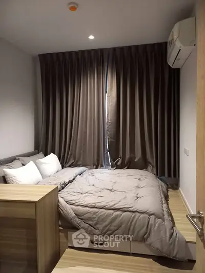 Cozy bedroom with modern decor and air conditioning, featuring elegant curtains and wooden flooring.