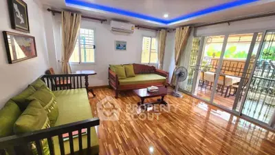 Spacious living room with wooden flooring and balcony access, perfect for relaxation and entertaining.