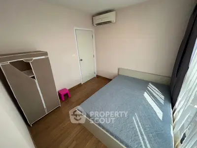 Cozy bedroom with air conditioning and natural light, featuring a minimalist design and wooden flooring.