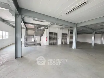 Spacious industrial warehouse with high ceilings and metal beams, ideal for storage or manufacturing.