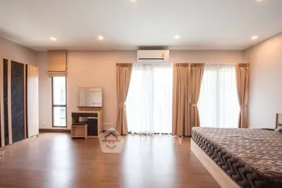 Spacious bedroom with modern decor and large windows for natural light.