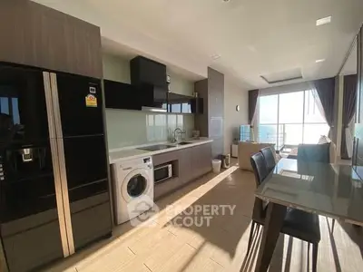 Modern kitchen with sleek appliances and open layout, leading to a bright living area with balcony view.