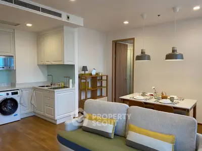 Modern open-plan living room with kitchen and dining area, featuring stylish decor and appliances.