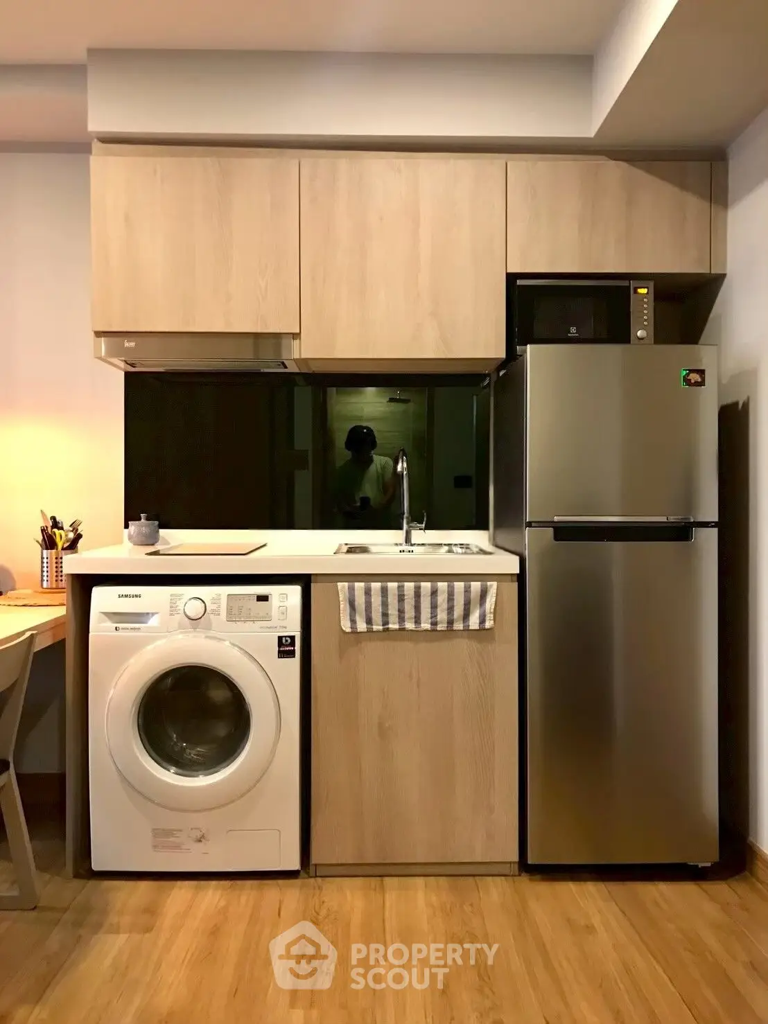 Modern compact kitchen with washing machine and fridge in cozy apartment