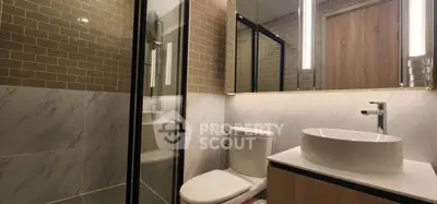 Modern bathroom with sleek design featuring glass shower and elegant fixtures.