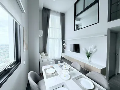 Modern high-ceiling living room with dining area and large windows