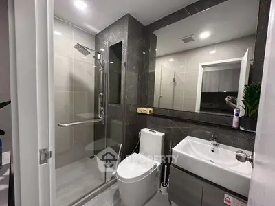 Modern bathroom with glass shower and sleek fixtures in contemporary apartment.