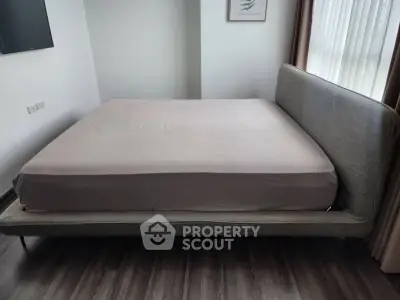Spacious bedroom with modern bed and natural light through large windows.