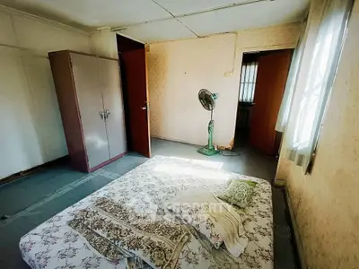 Cozy bedroom with minimalist decor and natural light, featuring a floor mattress and vintage fan.