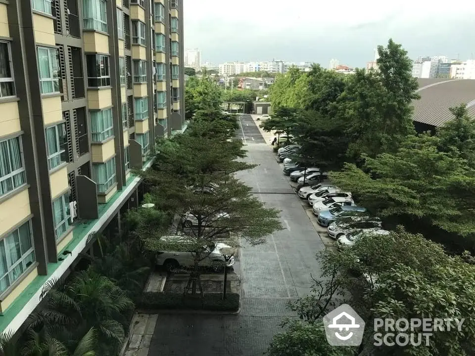 Spacious apartment building with lush greenery and ample parking space in urban setting.