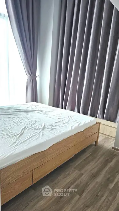 Spacious bedroom with modern wooden flooring and elegant curtains, perfect for a cozy retreat.