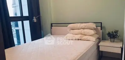 Cozy bedroom with large window and modern decor in urban apartment.