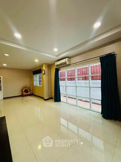 Spacious living room with large windows and modern lighting in a stylish home.