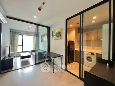Modern apartment with glass partitions, sleek kitchen, and cozy living area.
