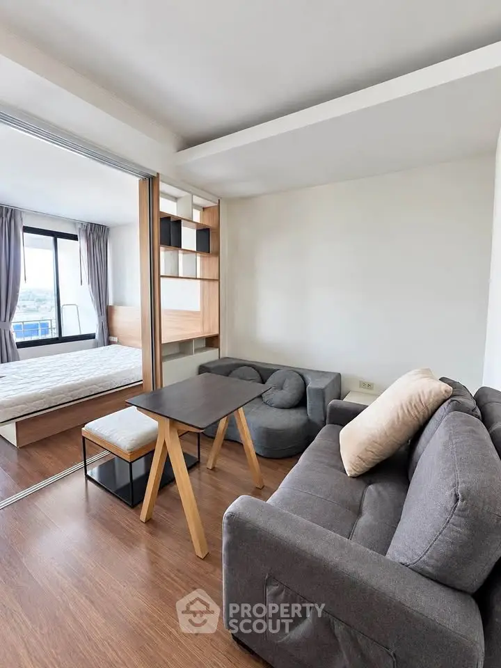 Modern studio apartment with cozy living area and bedroom, featuring stylish furniture and natural light.