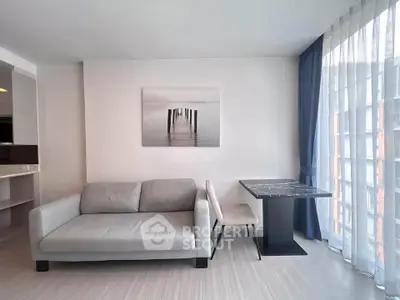 Modern living room with sleek gray sofa, elegant marble table, and large window with sheer curtains.