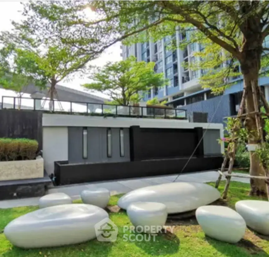 Modern apartment building exterior with landscaped garden and unique seating area.