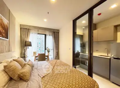 Modern bedroom with cozy decor and adjacent kitchen in a stylish apartment.