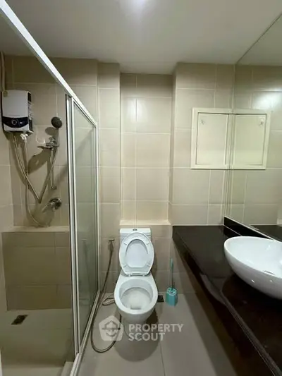 Modern bathroom with shower, toilet, and sleek countertop basin in a contemporary apartment.