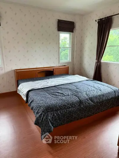 Spacious bedroom with large windows and elegant curtains, featuring a comfortable bed and stylish decor.