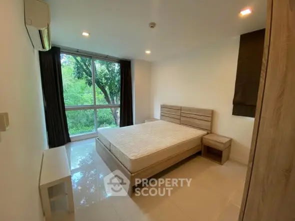 Spacious bedroom with large window and serene green view