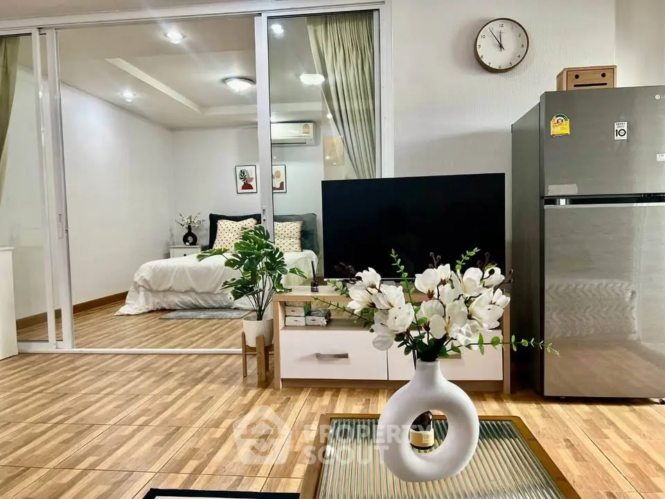Modern living room with stylish decor and view into cozy bedroom, featuring sleek flooring and elegant furnishings.