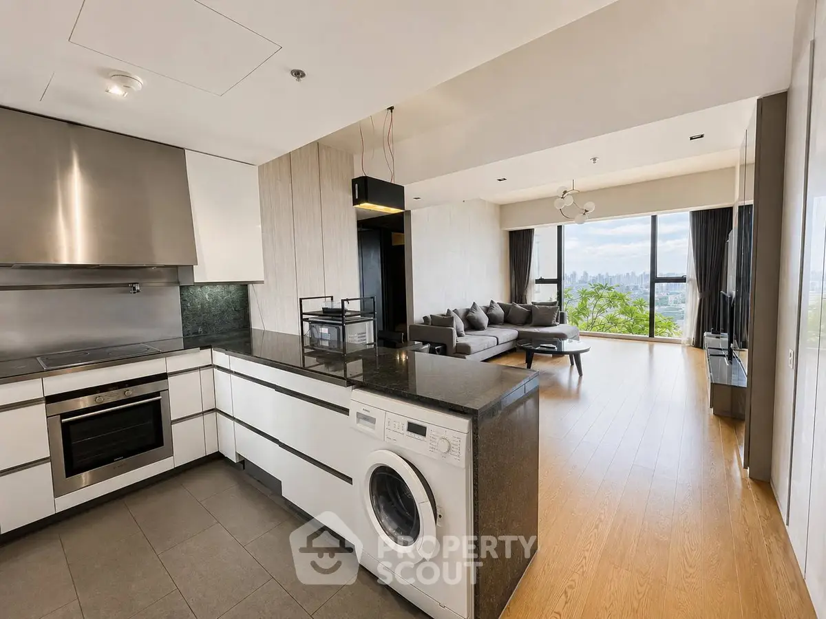 Modern open-plan kitchen and living room with city view, featuring sleek appliances and stylish decor.