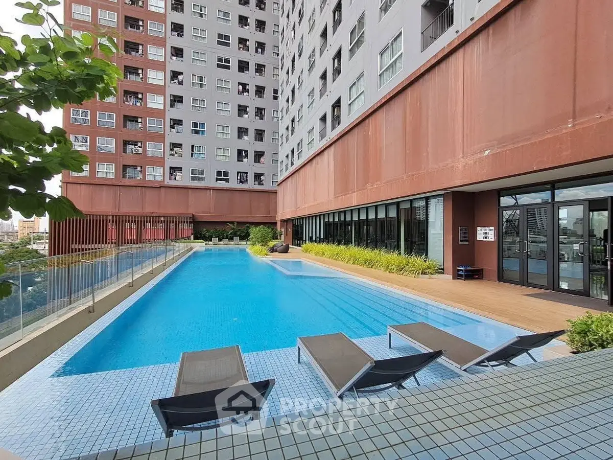 Modern apartment complex with inviting outdoor pool and sun loungers.