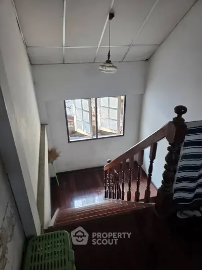 Charming staircase with wooden railing and natural light from window, perfect for cozy home ambiance.