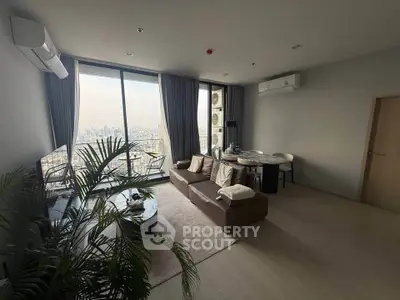 Spacious modern living room with city view, large windows, and stylish furniture in a high-rise apartment.