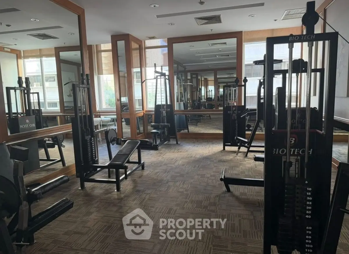 Spacious gym with modern fitness equipment and large mirrors in a residential building.