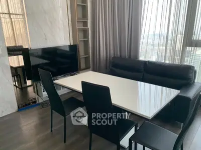 Modern living room with sleek furniture and large windows offering city views.