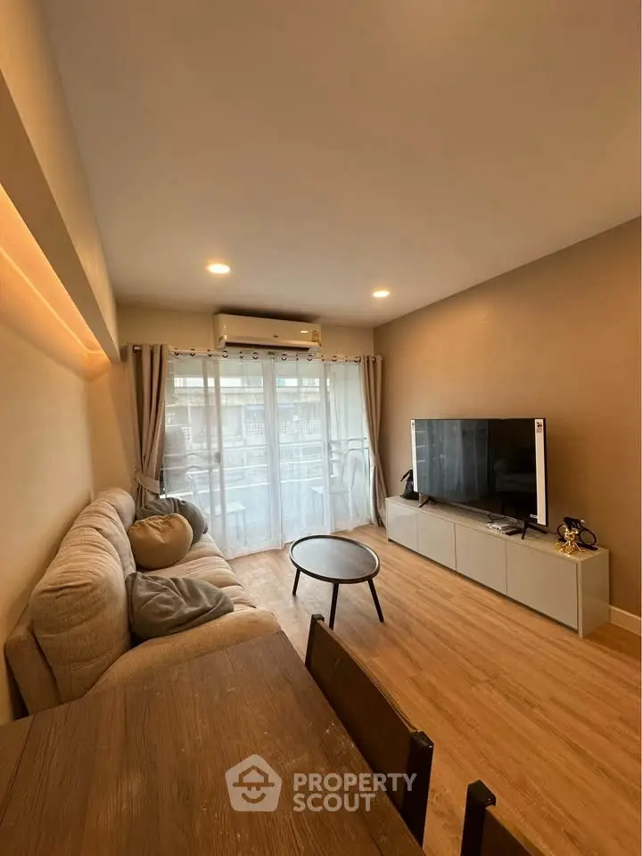 Modern living room with cozy sofa, TV, and balcony view.
