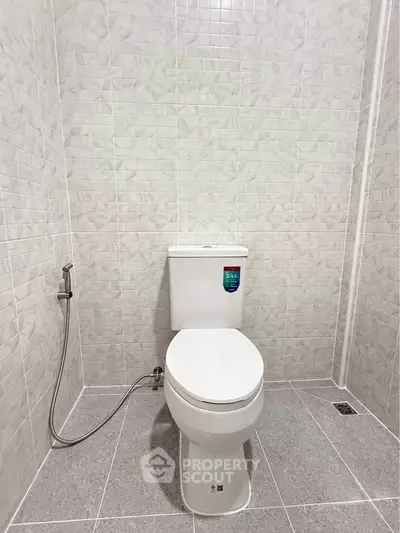 Modern bathroom with sleek white toilet and tiled walls, perfect for a minimalist home design.