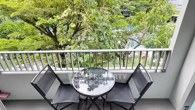 Charming balcony with lush green view and cozy seating area.