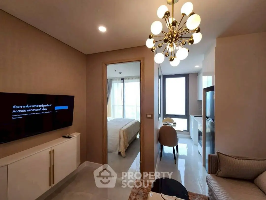 Modern apartment living room with elegant chandelier and cozy bedroom view.
