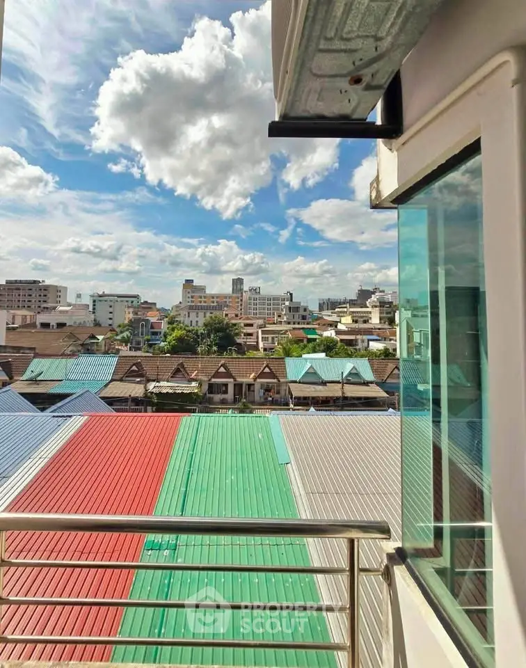 Stunning urban view from a modern balcony overlooking colorful rooftops and city skyline.