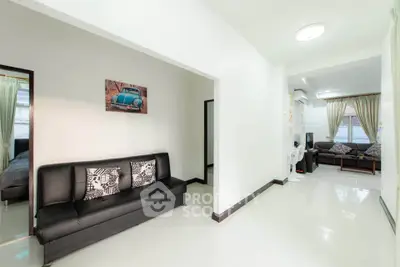 Spacious modern living room with sleek black sofas and bright natural lighting.