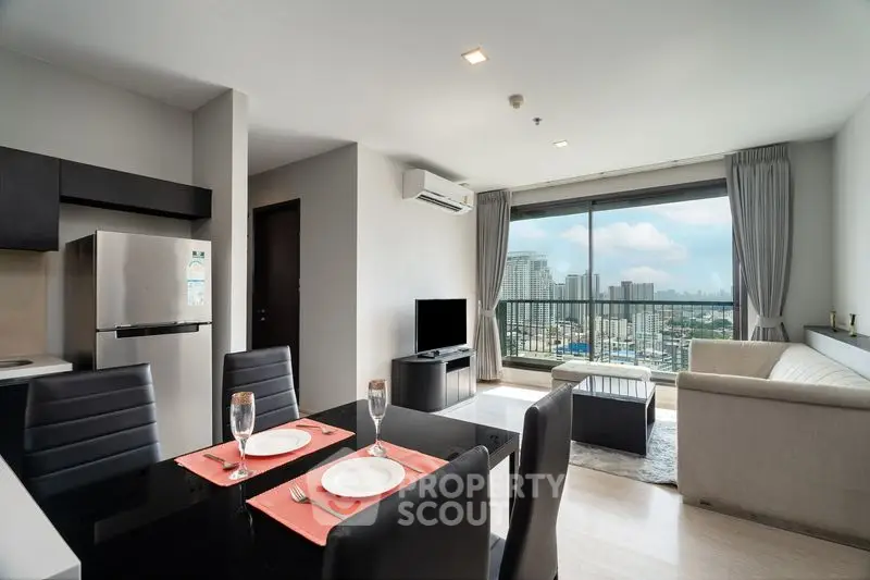 Modern open-plan living room with city view, featuring sleek furniture and large windows.
