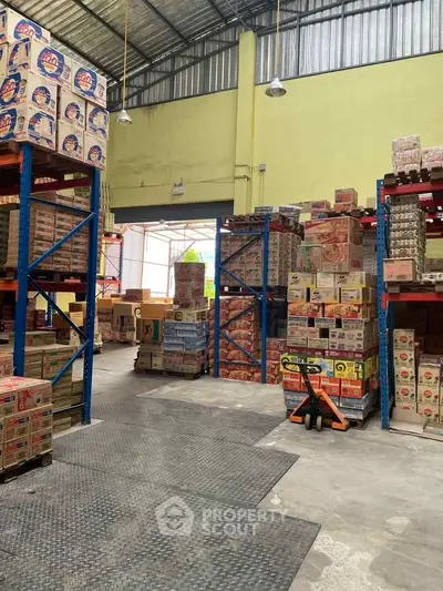 Spacious warehouse interior with stacked boxes and industrial shelving, ideal for storage and logistics operations.