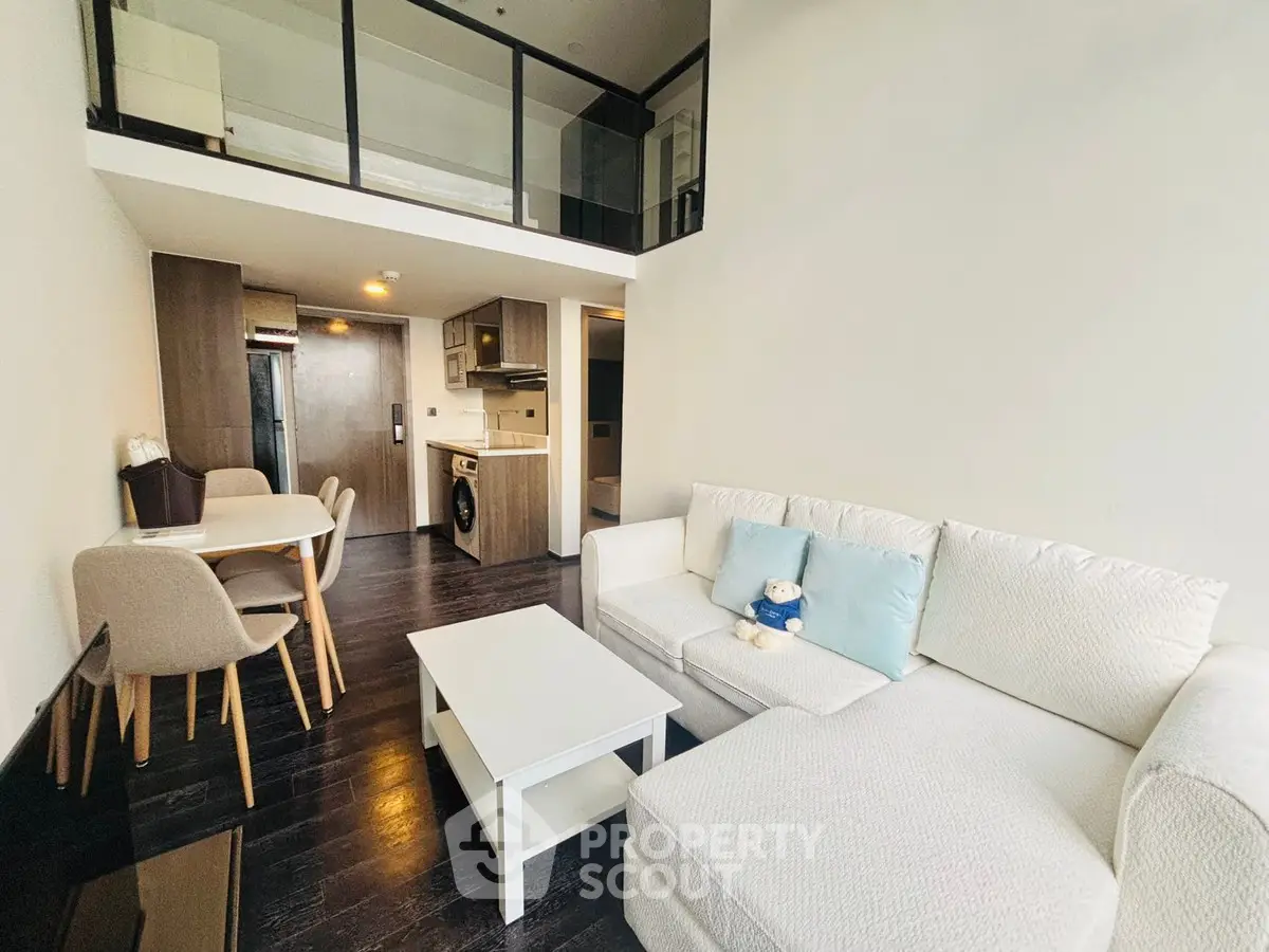 Modern loft-style living room with mezzanine, sleek furniture, and open kitchen layout.