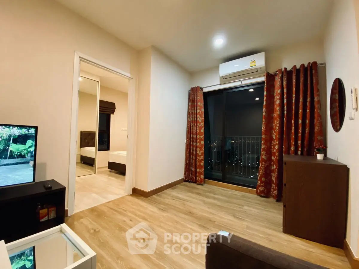 Modern living room with wooden flooring and balcony view in stylish apartment.