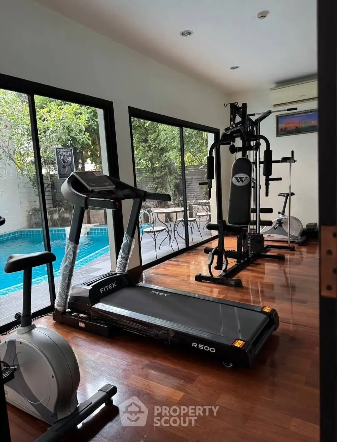Home gym with modern equipment and pool view, perfect for fitness enthusiasts seeking luxury living.