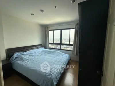 Cozy bedroom with city view, featuring a large bed and natural light.