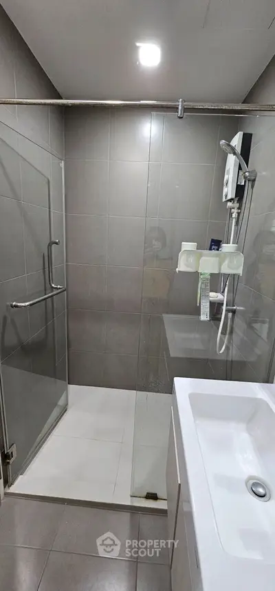 Modern bathroom with glass shower and sleek fixtures in contemporary apartment.