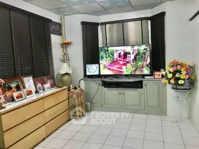 Cozy living room with TV, dresser, and floral decor in a charming home.