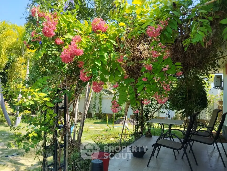 Charming garden patio with lush greenery and vibrant flowers, perfect for outdoor relaxation.