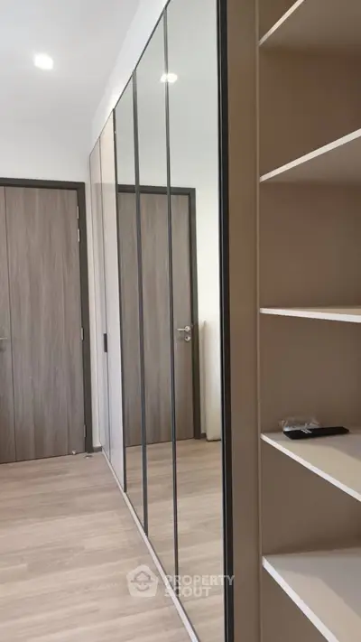 Modern bedroom with sleek mirrored wardrobe and wooden flooring